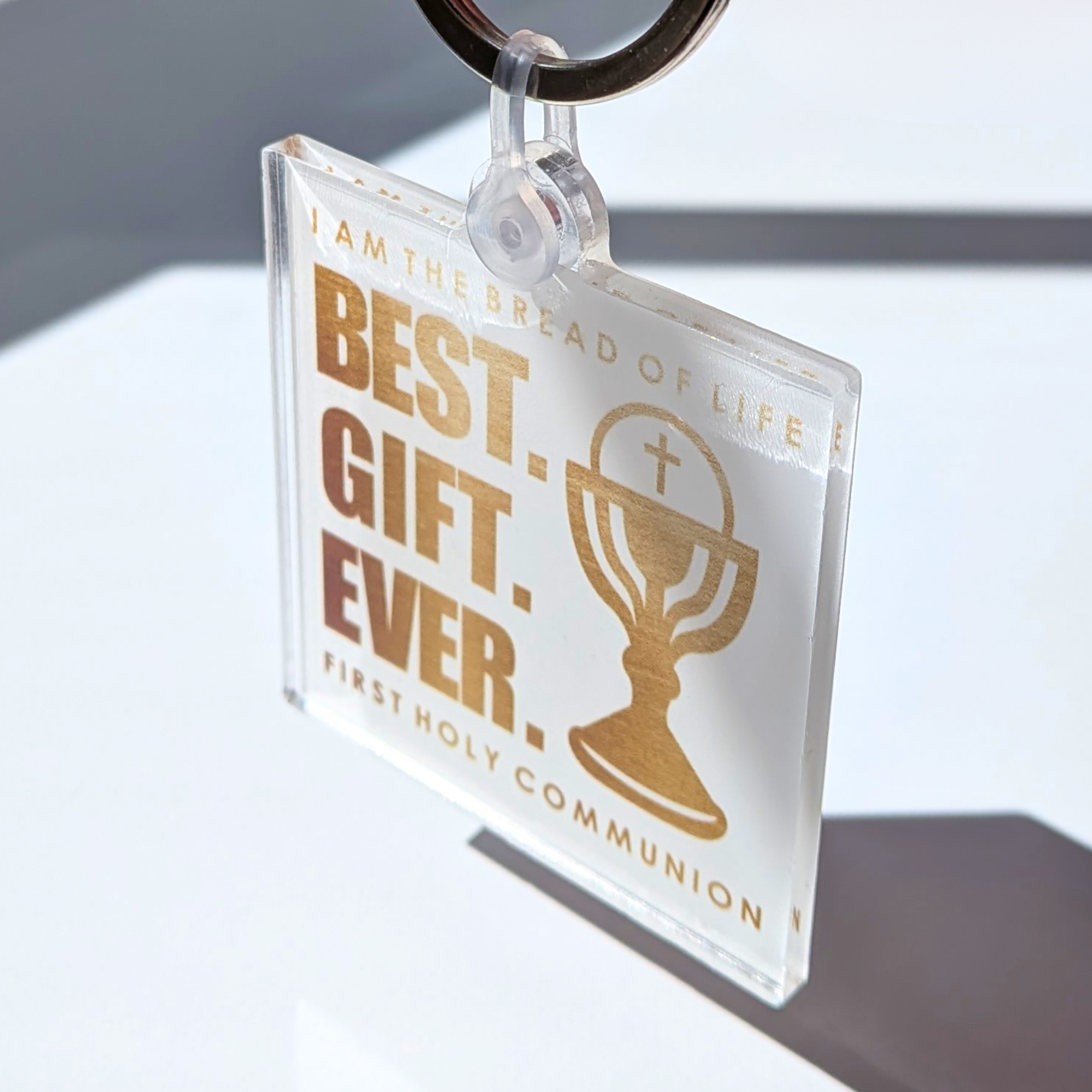 Clear keychain with gold text and design, featuring a cross and cup icon, on a light background.