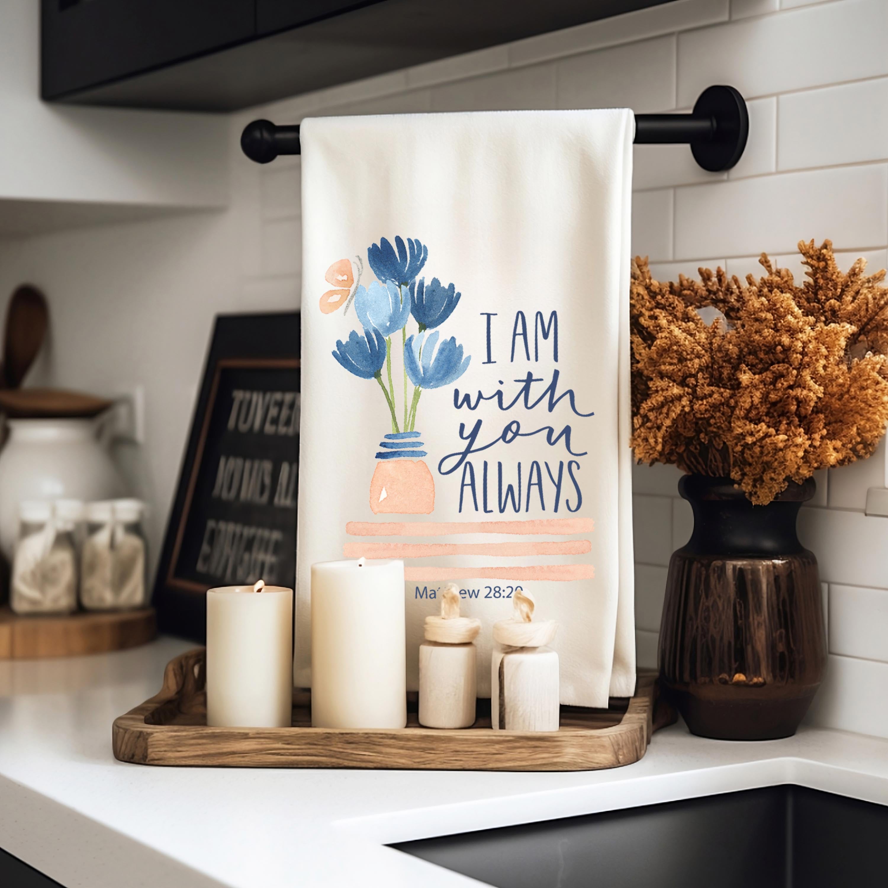 Christian kitchen towel with floral design and text "I Am With you Always" hanging on a rack in a kitchen, surrounded by candles and decor.