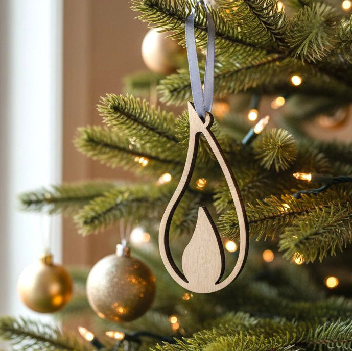 Decorative wooden flame ornament on a Christmas tree with lights and gold baubles.