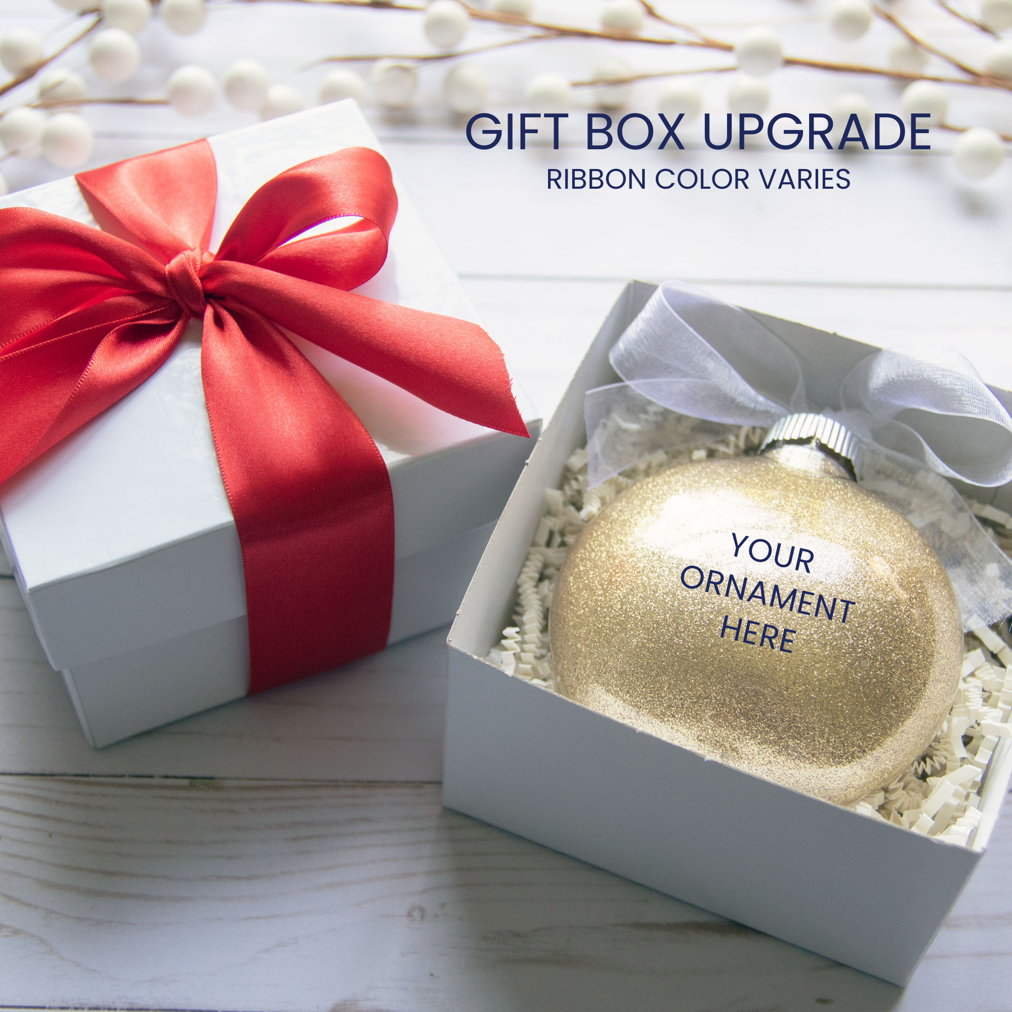 Gift box upgrade available. Ribbon color varies. Gift box with red double satin ribbon tied in a bow. Open gift box showing where ornament is placed.
