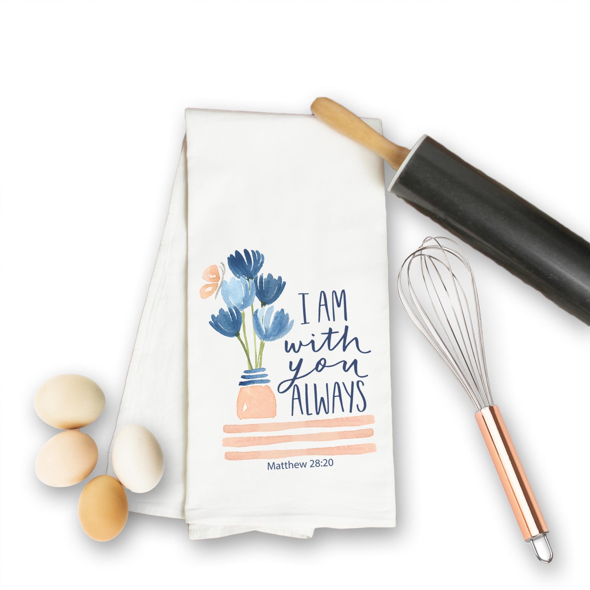 Christian kitchen towel with floral design and text, surrounded by eggs and kitchen tools on a white background