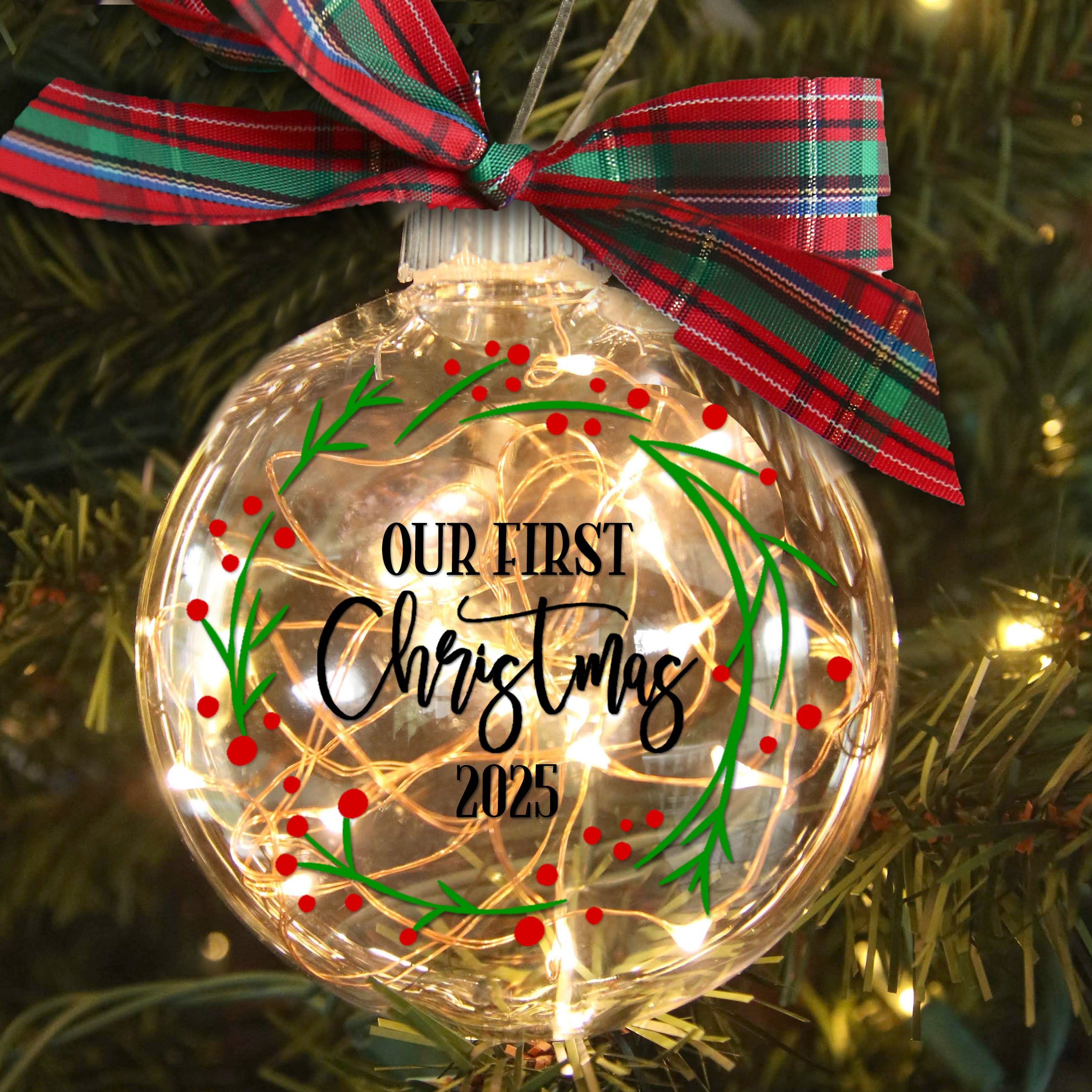 Decorative Christmas ornament with 'Our First Christmas 2025' text on a tree.
